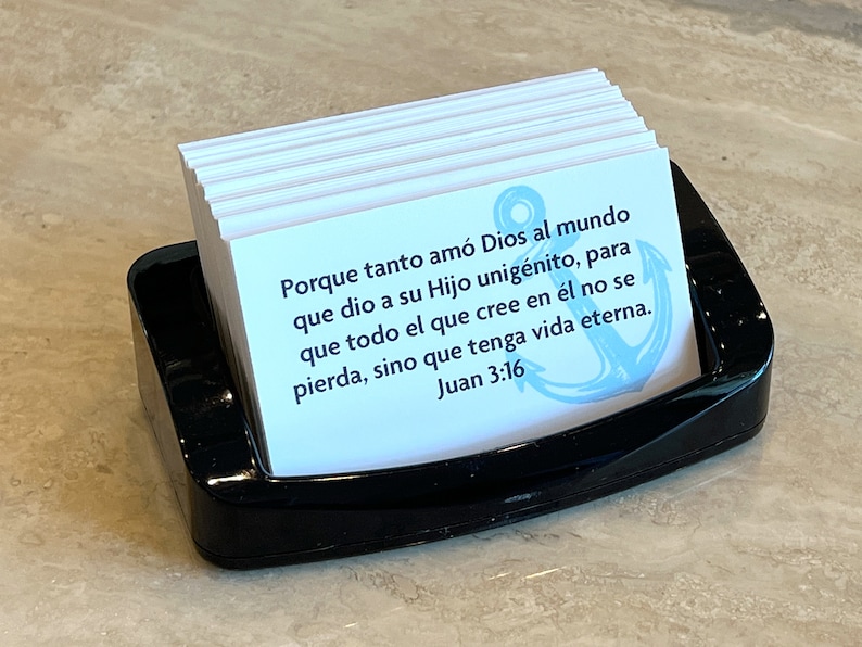 Op de afbeelding: Een stapel witte kaarten met een blauw anker en de tekst "Porque tanto am&oacute; Dios al mundo que dio a su Hijo unig&eacute;nito, para que todo el que cree en &eacute;l no se pierda, sino que tenga vida eterna. Juan 3:16" in het Spaans.