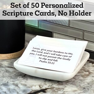 May include: A set of 50 white scripture cards with a verse from Psalm 55:22, "Lucas, give your burdens to Me, the Lord, and I will take care of you. I will not permit the Godly to slip and fall." The cards are stacked in a white ceramic dish on a grey countertop.