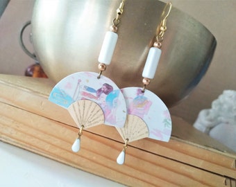 May include: A pair of gold earrings with white beads and a fan-shaped charm featuring a Japanese-inspired design with pink and blue watercolour accents.
