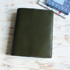 Puede incluir: Una cubierta de cuaderno de cuero verde oscuro con bordes cosidos.