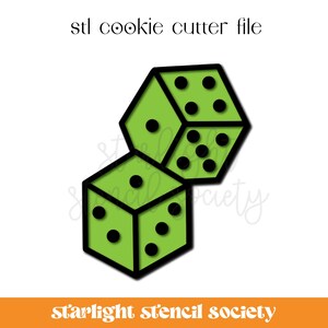 Pode incluir: Um cortador de biscoitos verde em forma de dois dados. Os dados estão empilhados um em cima do outro. O cortador de biscoitos é para fazer biscoitos em forma de dados.