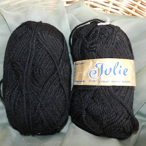 May include: Two balls of black yarn labeled "Jolie" with the text "DYLAN" "professeur" "machine washable" on the label.