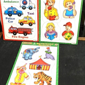 May include: Three colorful wooden preschool puzzles. One puzzle features emergency vehicles: ambulance, police car, fire engine, and taxi. Another puzzle shows people using phones and reading. The third puzzle depicts circus animals and a circus tent.