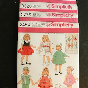 Puede incluir: Patrones de costura Simplicity apilados para ropa de muñecas. Los patrones presentan ilustraciones de trajes de muñecas, incluyendo vestidos y abrigos. Los patrones están etiquetados con tallas y el logotipo de Simplicity. La imagen incluye el texto "Sign-up for our free newsletter today at simplicity.com".