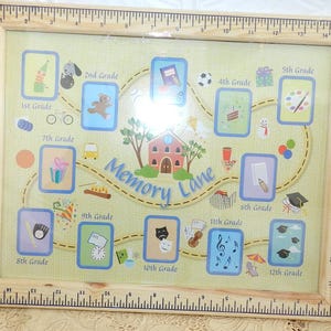 May include: A framed print with a ruler-style border. The print features a school-themed design with the words "Memory Lane" and grade levels from 1st to 12th grade. Each grade level has a corresponding icon.