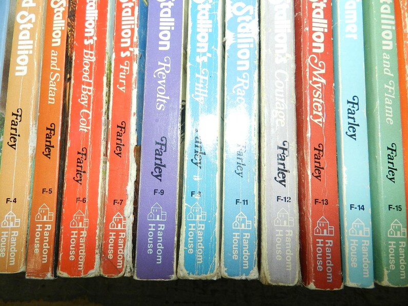 May include: A collection of vintage Farley books, featuring titles like "Stallion and Flame" and "Stallion's Mystery." The spines display various colors, with the author's name and publisher's logo visible. The books are arranged in a row.