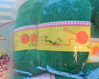 May include: Two balls of green yarn in plastic packaging. The label reads "Crystals" and features a bird and a ball of yarn.