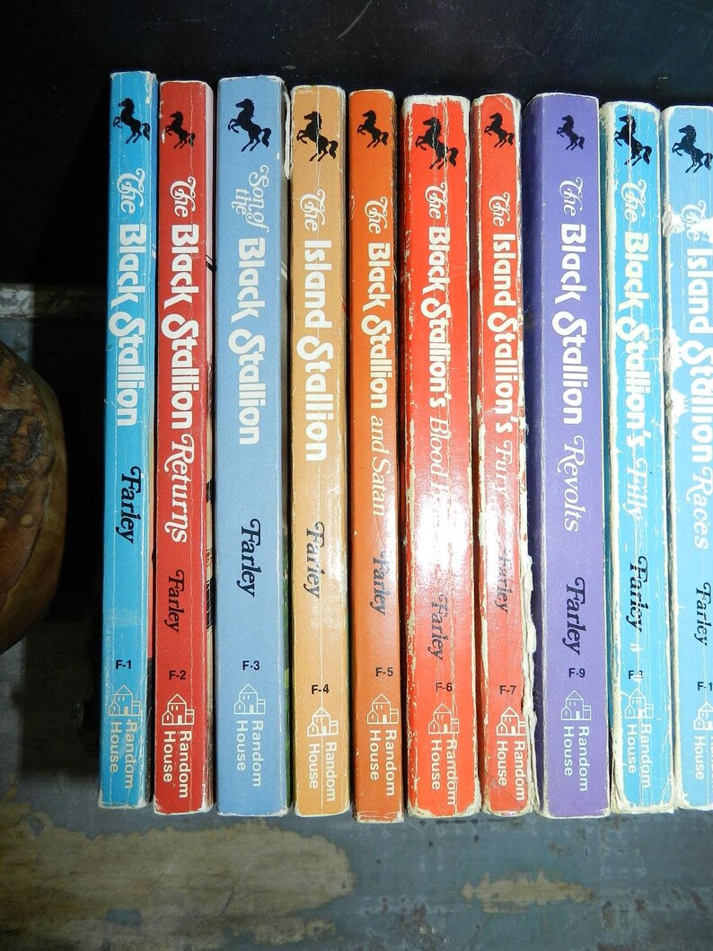 May include: A collection of vintage "The Black Stallion" book series by Walter Farley. The spines are various colors, including blue, red, orange, and purple, with black horse illustrations. The books are published by Random House.