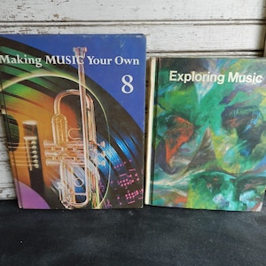 Puede incluir: Dos libros de texto de música antiguos. Uno se titula "Making Music Your Own 8" con un gráfico de trompeta. El otro libro se titula "Exploring Music 6" con un diseño abstracto verde y azul.