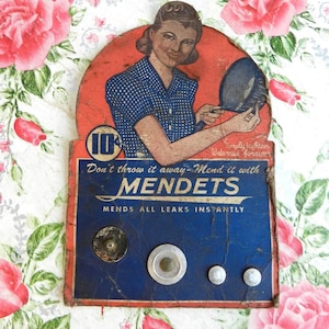 May include: Vintage MENDETS advertisement featuring a woman in a blue polka-dot dress. The sign is blue and red with the text "Don't throw it away-Mend it with MENDETS" and "MENDS ALL LEAKS INSTANTLY". The price is 10 cents.