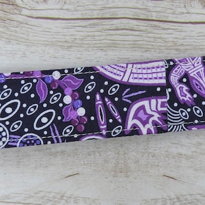 May include: Purple and white patterned fabric key chain with a gold metal clasp.