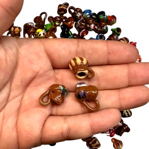 May include: A collection of small, hand-painted ceramic mugs with various colors and designs. The mugs are brown with white, yellow, and blue accents.