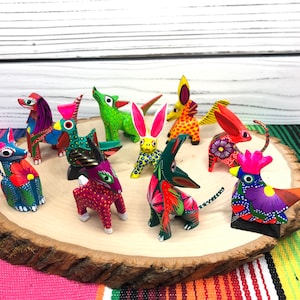 May include: A collection of ten hand-painted wooden animal figurines. The figurines are brightly colored and feature a variety of animals, including a rooster, a rabbit, a cat, and a dog. The figurines are arranged on a wooden slice.