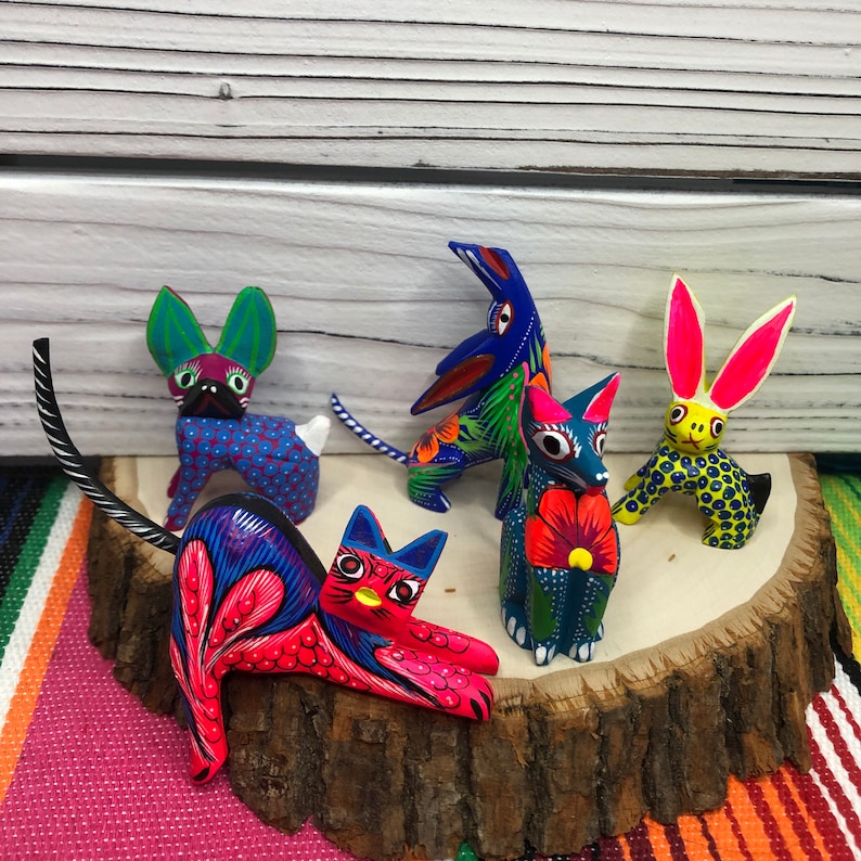 K&ouml;nnte beinhalten: F&uuml;nf bunte, handbemalte Holzfiguren von Tieren. Die Figuren umfassen eine Katze, ein Kaninchen, einen Hund und zwei V&ouml;gel. Die Figuren sind alle leuchtend bunt und haben komplizierte Details.