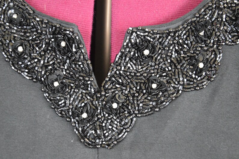 May include: A black shirt with a beaded neckline. The beads are arranged in a floral pattern.