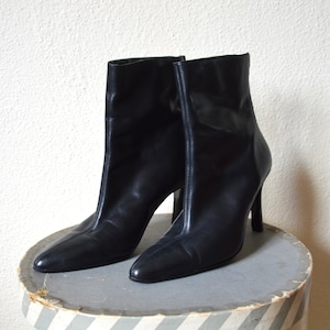 May include: A pair of black leather ankle boots with stiletto heels.