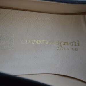 Puede incluir: Primer plano del interior de un zapato negro con una plantilla de cuero blanco. La plantilla tiene el texto "La Porta Benoli" y "Made in Italy" impreso en dorado.