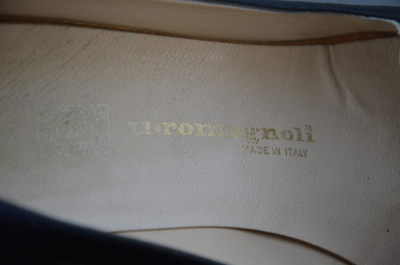 Puede incluir: Primer plano del interior de un zapato negro con una plantilla de cuero blanco. La plantilla tiene el texto "La Porta Benoli" y "Made in Italy" impreso en dorado.