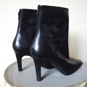 May include: A pair of black leather ankle boots with a pointed toe and stiletto heels.