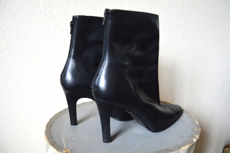 May include: A pair of black leather ankle boots with a pointed toe and stiletto heels.