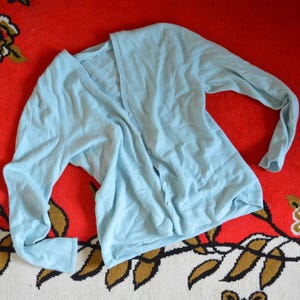 May include: A light blue cardigan sweater with a V-neck and button closure.