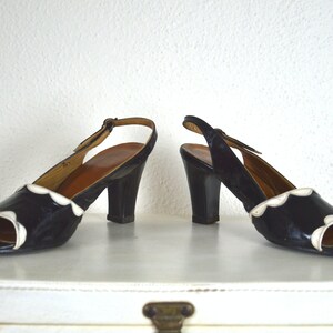 May include: A pair of black and white heeled shoes with a scalloped edge. The shoes have a slingback strap and a closed toe.