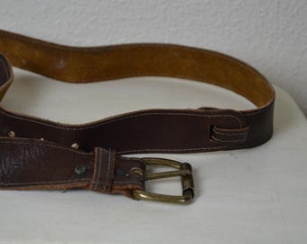 May include: A brown leather belt with a brass buckle. The belt has a double layer of leather and a stitched design.