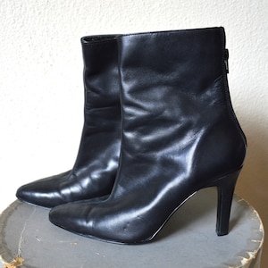 May include: A pair of black leather ankle boots with a pointed toe and stiletto heels.