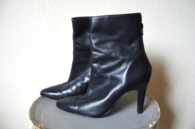 May include: A pair of black leather ankle boots with a pointed toe and stiletto heels.