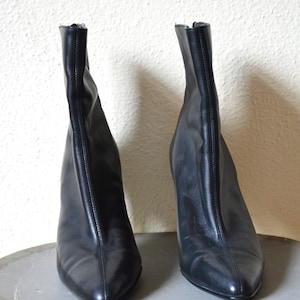 May include: A pair of black leather ankle boots with pointed toes and stiletto heels.