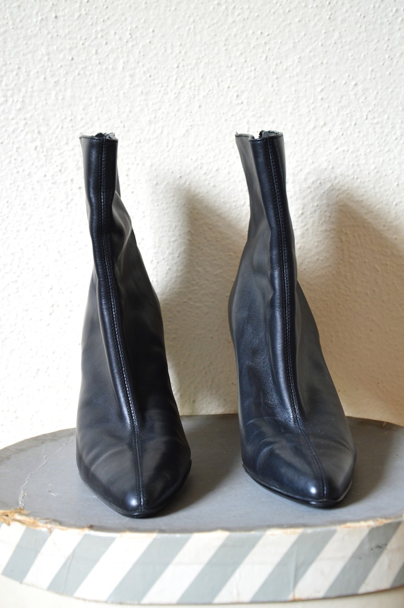 May include: A pair of black leather ankle boots with pointed toes and stiletto heels.