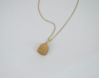 May include: A gold chain necklace with a light brown, irregularly shaped pendant.