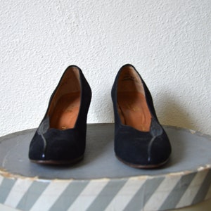 May include: A pair of black suede heeled pumps with a pointed toe.
