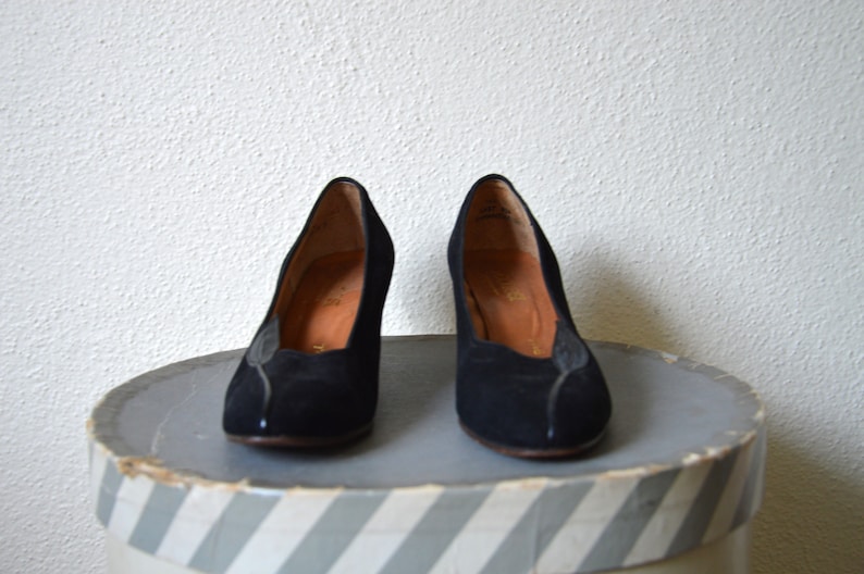 May include: A pair of black suede heeled pumps with a pointed toe.