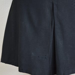 May include: Black knee-length dress with a single back vent and a straight skirt.