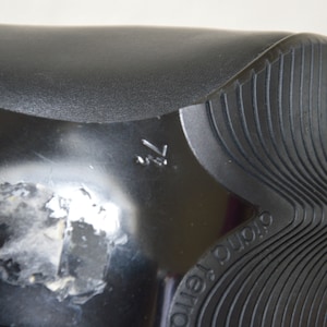 May include: Close-up of the bottom of a black shoe with a textured sole. The sole has the word "DURO" printed on it.