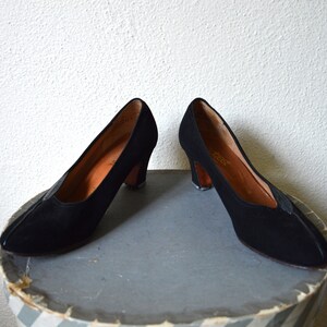 May include: A pair of black suede heeled shoes with a pointed toe.