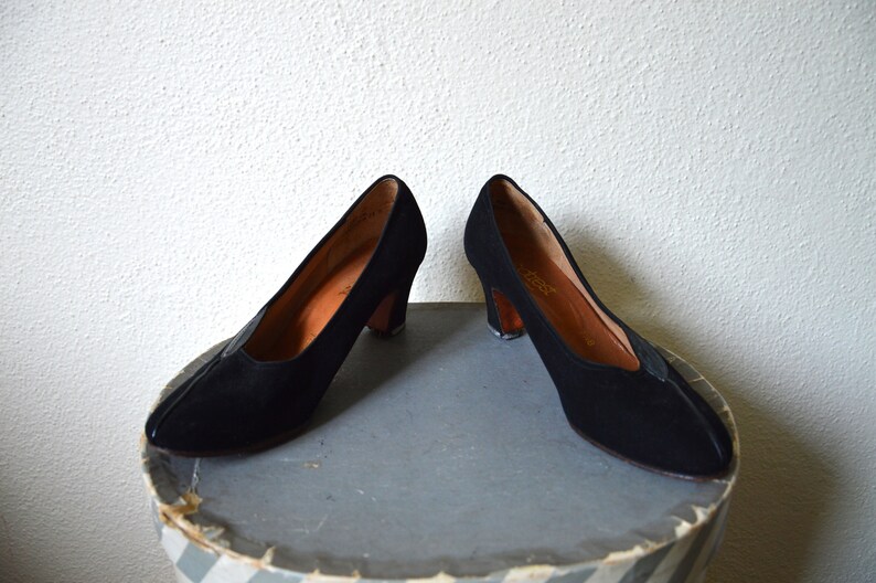 May include: A pair of black suede heeled shoes with a pointed toe.