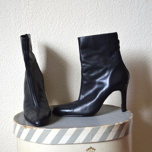 May include: A pair of black leather ankle boots with stiletto heels. The boots have a pointed toe and a zipper on the back.