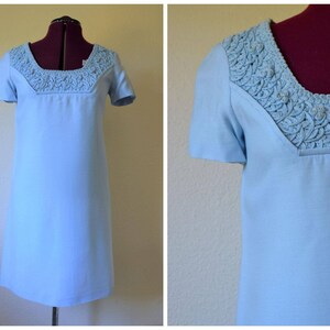 May include: A light blue short-sleeved dress with a white crocheted neckline.