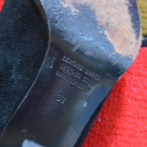 May include: Close-up of the sole of a black shoe. The sole is marked with the words "LEATHER UPPER, LEATHER SOLE, MADE IN ITALY" and the number "39". The shoe's sole shows signs of wear.