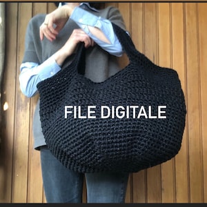 Può includere: Una grande borsa tote in crochet nero con una superficie testurizzata. La borsa è tenuta da una persona e il testo "FILE DIGITALE" è visibile sulla borsa.