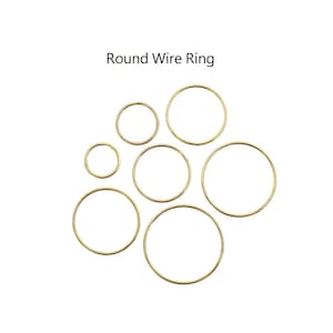 以下が含まれることがあります： さまざまなサイズの金色の丸いワイヤーリングのコレクションが、白い背景に配置されています。「Round Wire Ring」というテキストがリングの上に表示されています。これらのリングは、ジュエリー作りやクラフトプロジェクトに適しています。