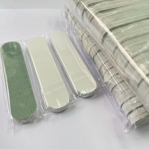 May include: A selection of nail files, some individually packaged in clear plastic. The files are rectangular with rounded ends. One is green, and the others are white. A large stack of files is visible in the background.