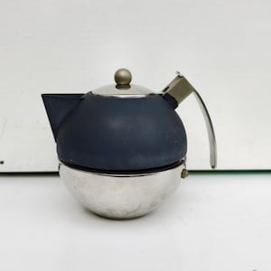 May include: A silver and black teapot with a round body and a single handle. The teapot has a lid with a small knob on top.