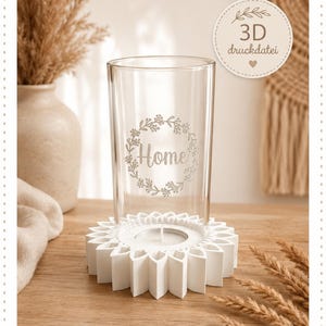May include: A clear glass cylinder featuring a floral wreath design with the word Home in the center, resting on a white, circular, petal-shaped base. A circular badge in the upper right corner displays the text 3D druckdatei with a heart icon.