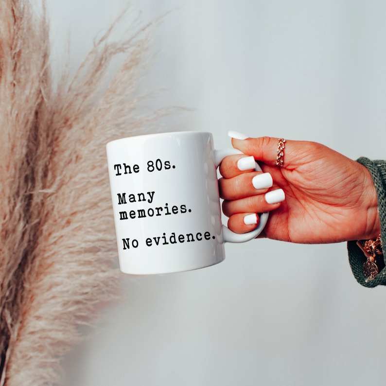 May include: White ceramic mug with black text that reads "The 80s. Many memories. No evidence."