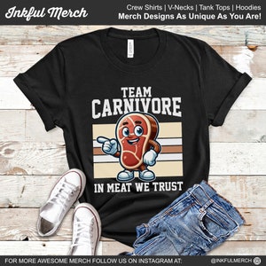 May include: Black t-shirt with a cartoon steak graphic and the text "Team Carnivore" and "In Meat We Trust".