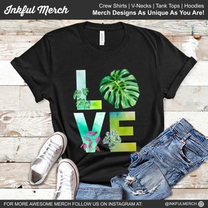 May include: Black t-shirt with a watercolor design of the word "LOVE" with green leaves and plants. The text "Inkful Merch" is at the top of the image. The text "Crew Shirts | V-Necks | Tank Tops | Hoodies" is at the top of the image. The text "Merch Designs As Unique As You Are!" is at the top of the image. The text "FOR MORE AWESOME MERCH FOLLOW US ON INSTAGRAM AT: @INKFULMERCH" is at the bottom of the image.