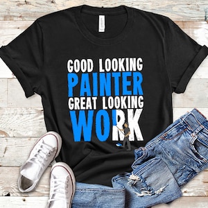 May include: Black t-shirt with white text that reads "Good Looking Painter Great Looking Work". The text is in blue and there is a small illustration of a painter holding a paint roller.